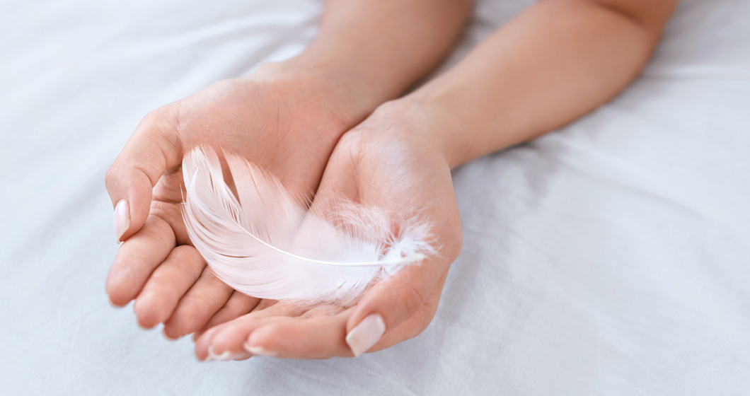 Hand holding a feather to symbolize the soothing abilities of the anti-inflammation product range